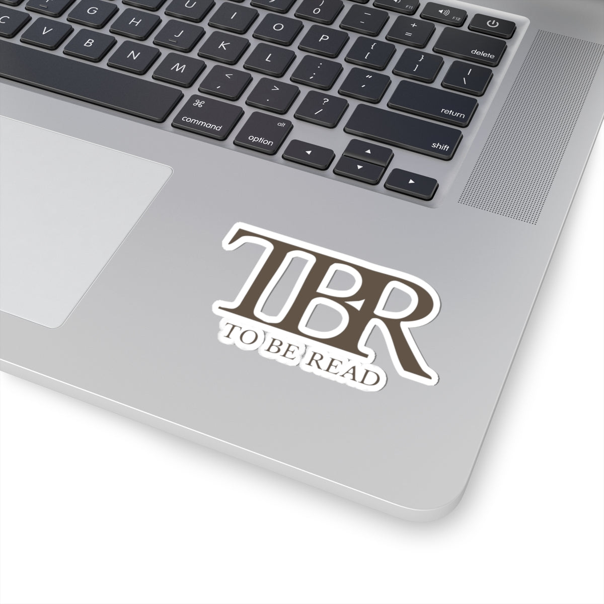 Thtgrlreads TBR sticker with bold, serif font reading "To Be Read," part of the Book Bestie and Off Brand collections, shown on a laptop surface.