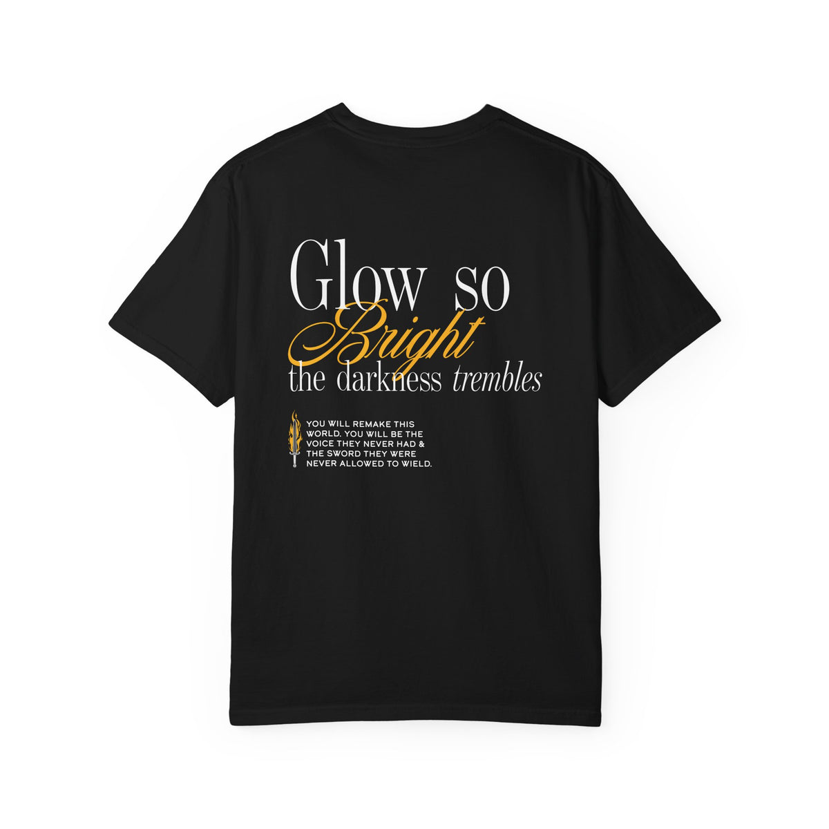 Kindred's Curse Saga Comfort Colors graphic tee from thtgrlreads featuring a vintage washed black fabric with white and gold script text reading "Glow so bright the darkness trembles" from the Glow So Bright | Diem Bellator Tee collection.