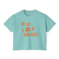 Thtgrlreads women's cropped Comfort Colors tee from The Life of a Book Bestie collection featuring vintage orange text and stacked books graphic on a soft light blue fabric.