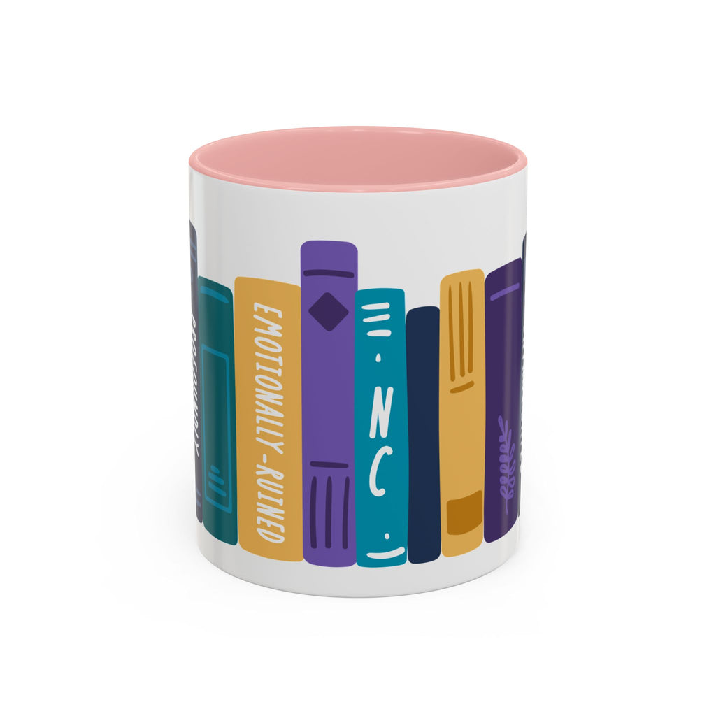 A white ceramic mug with a soft pink interior featuring a colorful graphic of stylized book spines in teal, purple, yellow, and blue tones wrapped around the exterior.