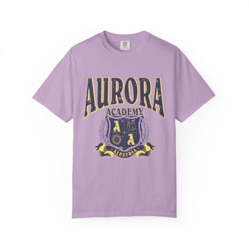 A vintage wash lilac Comfort Colors graphic tee from thtgrlreads featuring a distressed print of Aurora Academy with a crest emblem, part of the Ruthless Boys of the Zodiac and Back to School collections.