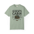 Sage green Comfort Colors graphic tee featuring a cabin, pine trees, and Koen's Cabin design from Ali Hazelwood, by Thtgrlreads, in Tees and Ali Hazelwood.
