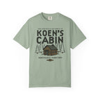 Sage green Comfort Colors graphic tee featuring a cabin, pine trees, and Koen's Cabin design from Ali Hazelwood, by Thtgrlreads, in Tees and Ali Hazelwood.