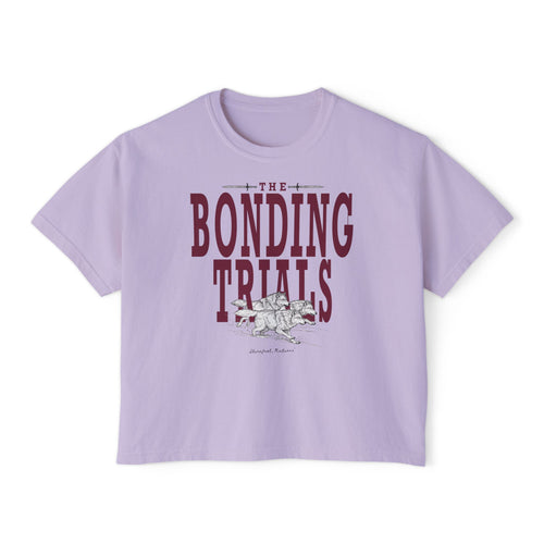 thtgrlreads Wolves of Ruin collection features a lavender Comfort Colors crop top with vintage wash, bold maroon "The Bonding Trials" text, and a detailed wolf graphic.