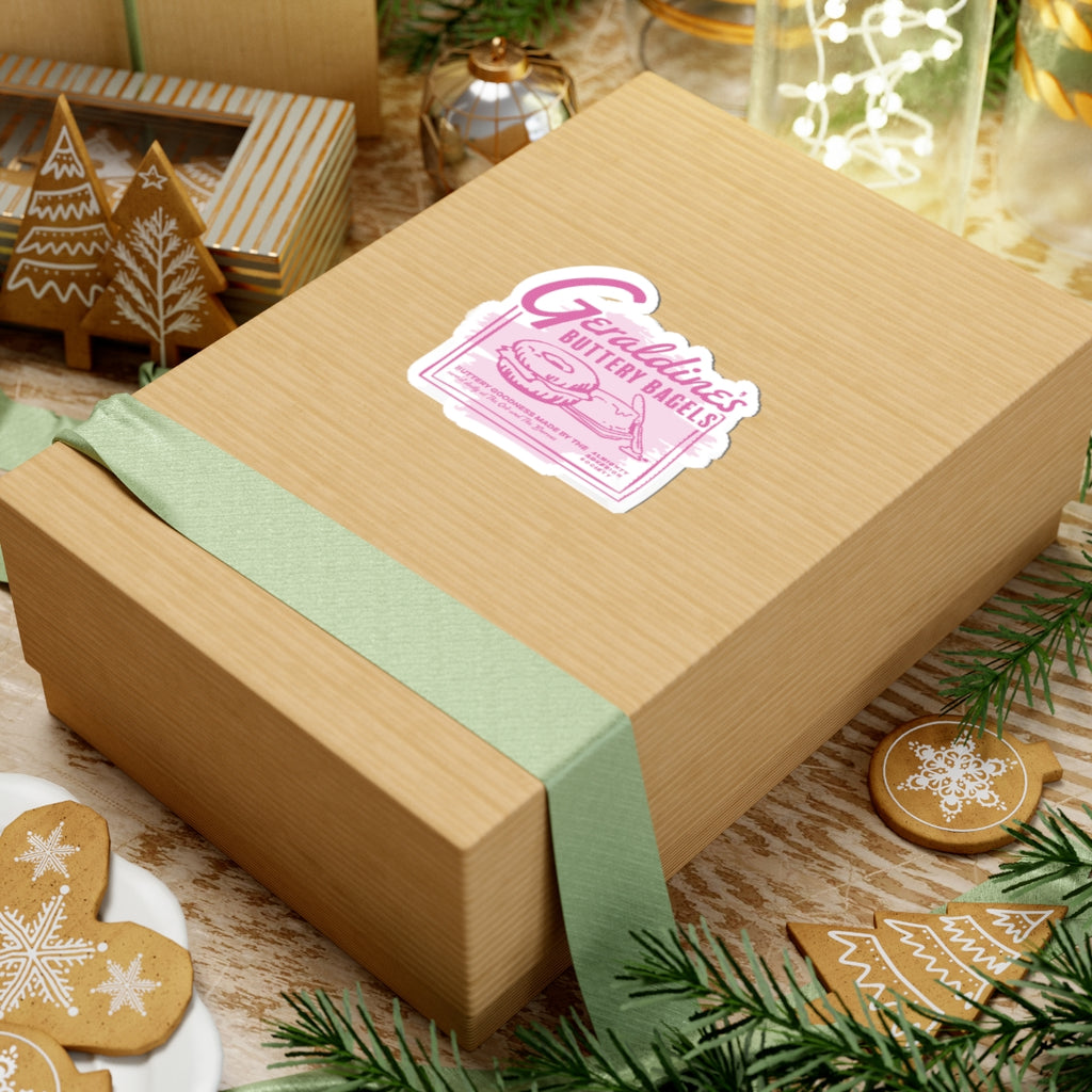 Zodiac Academy themed Geraldine's Bagels sticker from thtgrlreads displayed on a kraft gift box with a pale green ribbon, surrounded by festive gingerbread cookies and holiday decor.