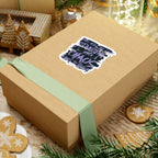 A brown gift box wrapped with a light green ribbon featuring a thtgrlreads Chaos Sticker from the Lady of Darkness & Legacy Series collection, surrounded by holiday-themed decorated gingerbread cookies and festive ornaments.