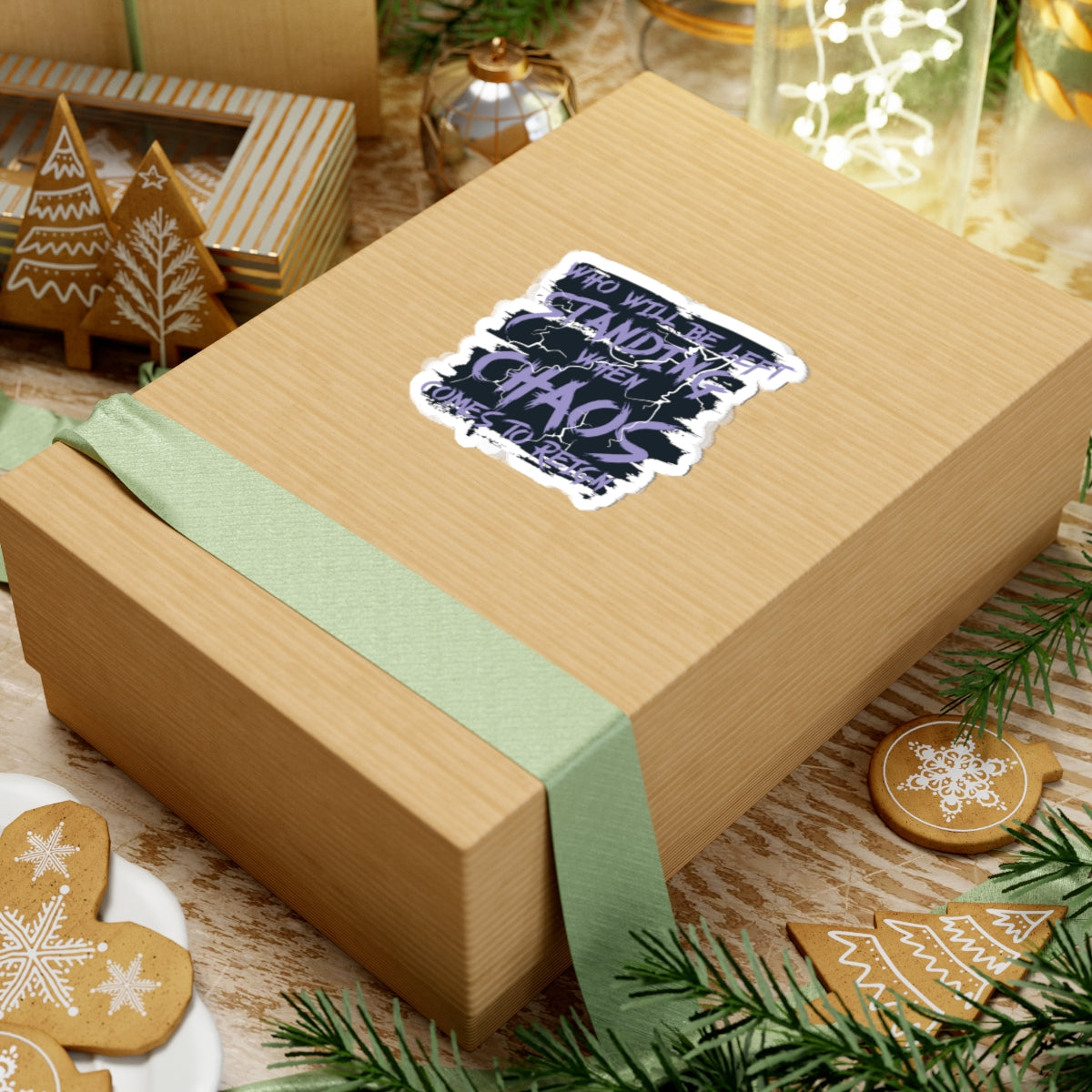 A brown gift box wrapped with a light green ribbon featuring a thtgrlreads Chaos Sticker from the Lady of Darkness & Legacy Series collection, surrounded by holiday-themed decorated gingerbread cookies and festive ornaments.