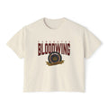 A cream-colored unisex Comfort Colors cropped t-shirt featuring a vintage wash and bold Bloodwing Academy graphic text with a circular emblem in maroon and gold, thtgrlreads.