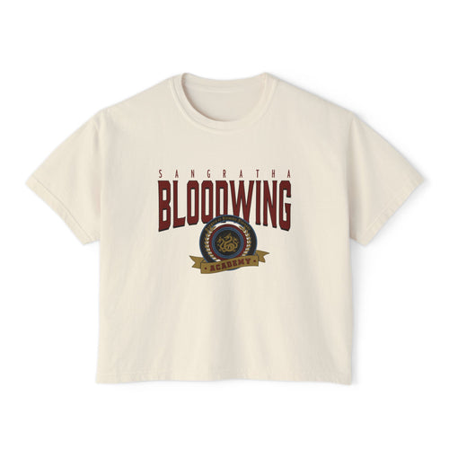 A cream-colored unisex Comfort Colors cropped t-shirt featuring a vintage wash and bold Bloodwing Academy graphic text with a circular emblem in maroon and gold, thtgrlreads.