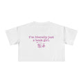 thtgrlreads officially licensed bookish apparel features this Printify white Comfort Colors crop top with vintage wash, soft fabric, and a purple graphic saying "I'm literally just a book girl" above a stack of books illustration, part of the Tees collection.