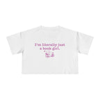 thtgrlreads officially licensed bookish apparel features this Printify white Comfort Colors crop top with vintage wash, soft fabric, and a purple graphic saying "I'm literally just a book girl" above a stack of books illustration, part of the Tees collection.