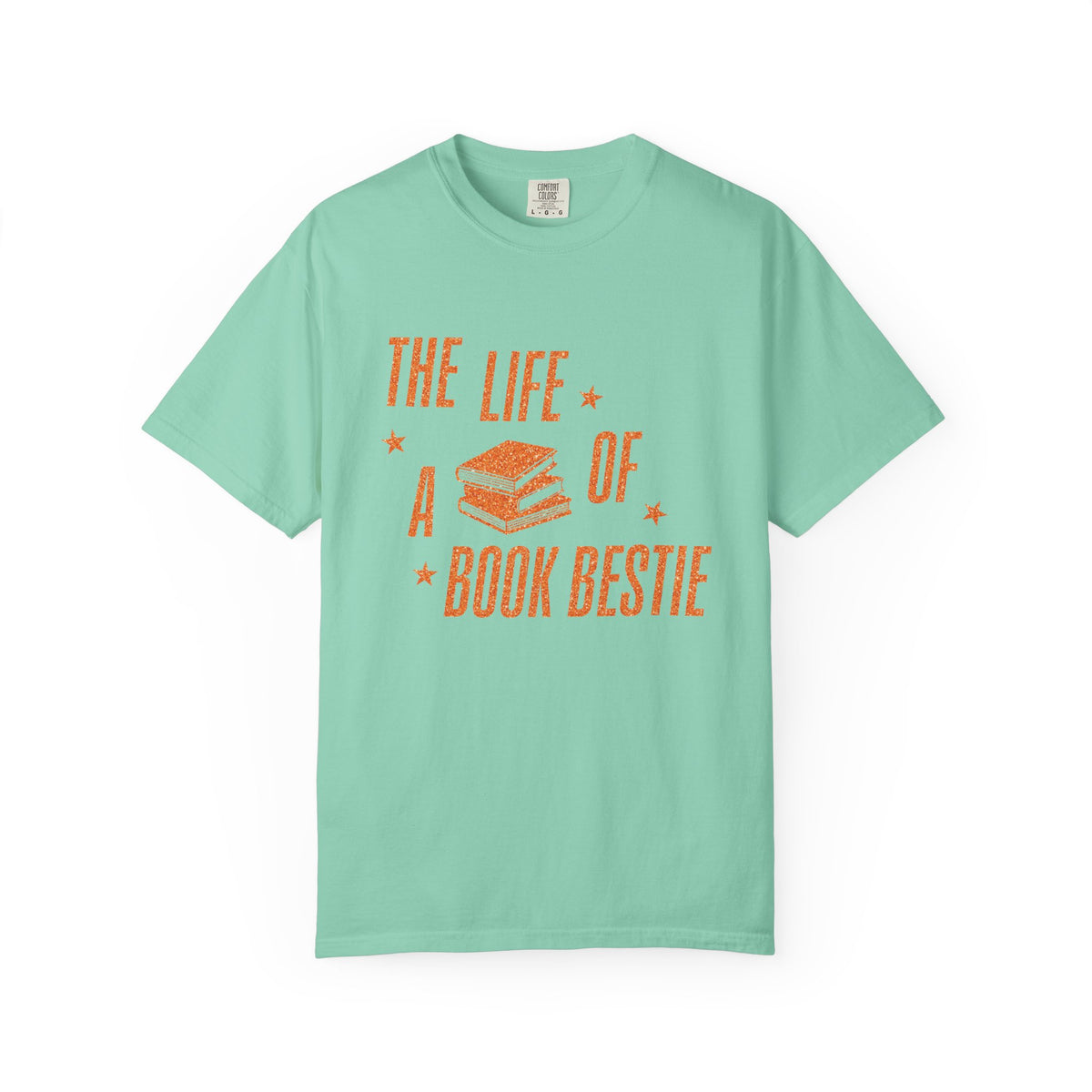 A mint Comfort Colors graphic tee from thtgrlreads featuring a vintage-style orange print of stacked books and the phrase "The Life of a Book Bestie," part of the Book Bestie collection.