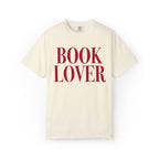 Thtgrlreads comfort colors graphic tee from the Tees collection featuring a vintage-wash cream base with bold red serif text reading "BOOK LOVER" on the front.