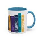 White ceramic mug with a blue handle and interior featuring colorful book spine illustrations labeled "Introverted" and "Scholars," a cozy design from thtgrlreads.