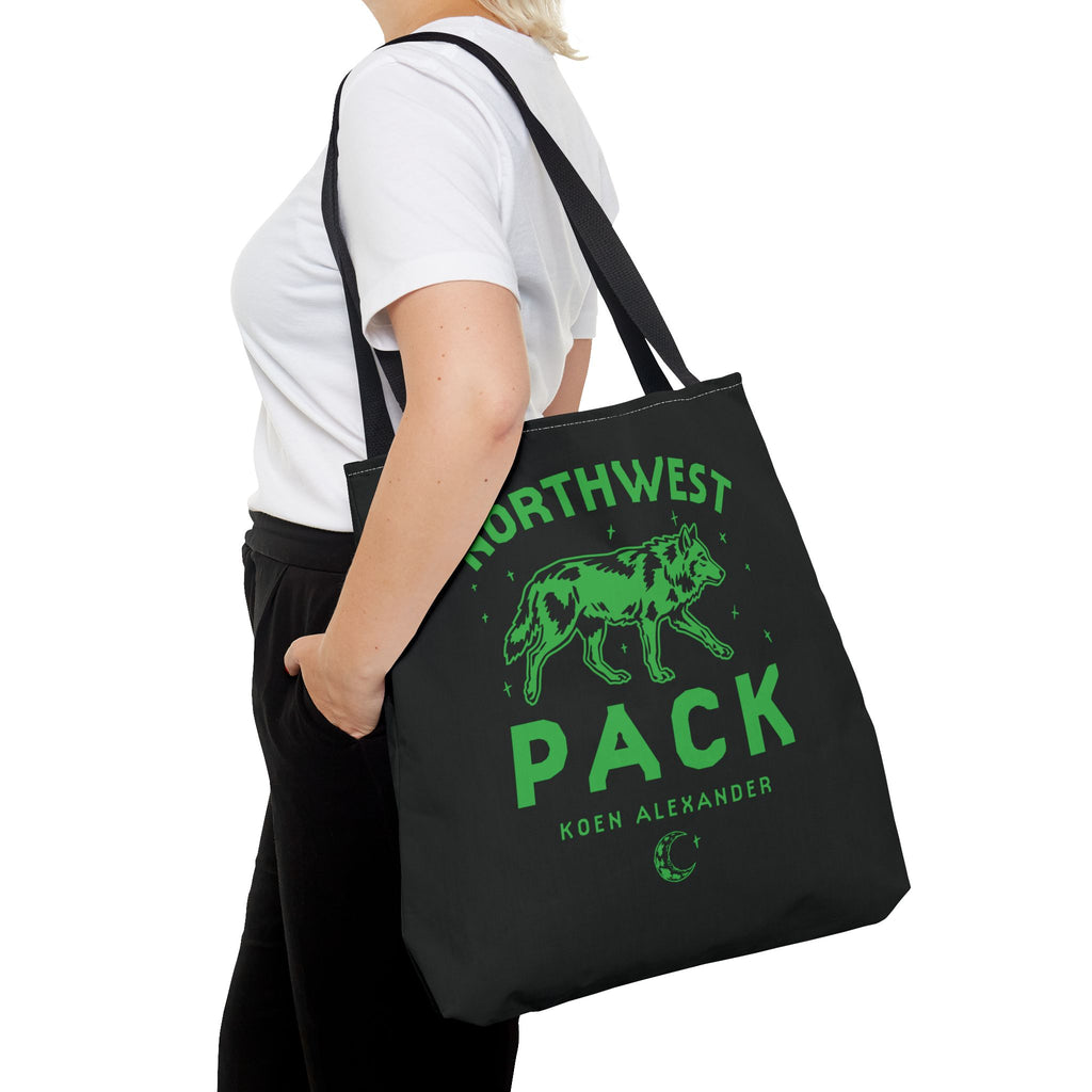 Black Northwest Pack tote bag with a green wolf graphic and Koen Alexander text, carried over the shoulder as Ali Hazelwood licensed bookish merch by Printify