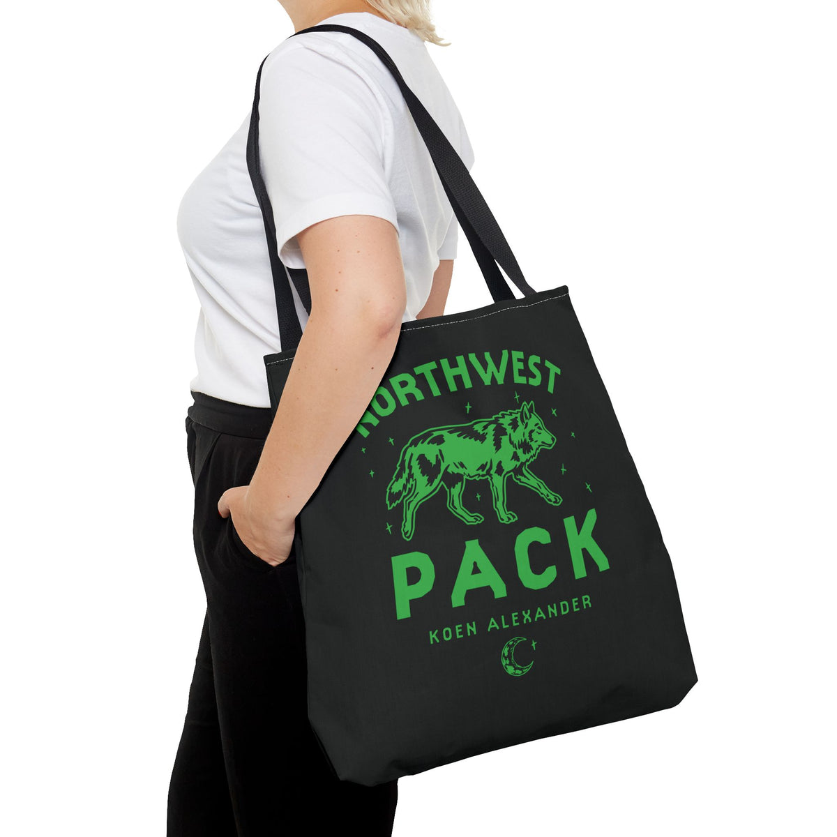 Black Northwest Pack tote bag with a green wolf graphic and Koen Alexander text, carried over the shoulder as Ali Hazelwood licensed bookish merch by Printify