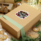 A thtgrlreads Liv Zander collection sticker featuring a detailed skull with a gold crown surrounded by red roses, placed on a brown gift box with a soft green ribbon, surrounded by festive holiday cookies and decorations.